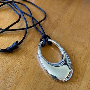 Costume jewelry, silver pendant on thin black velvet cord.